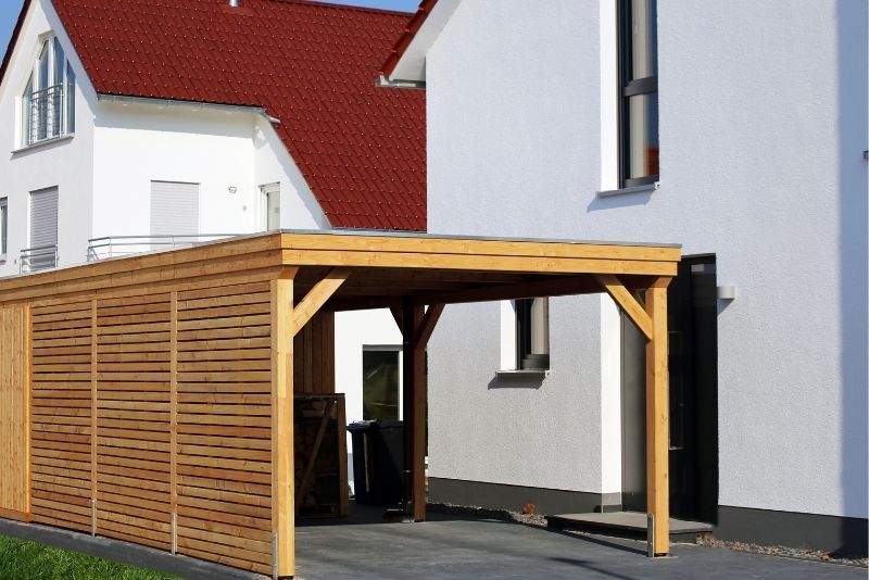 Timber-clad carport built onto the side of a two-storey home