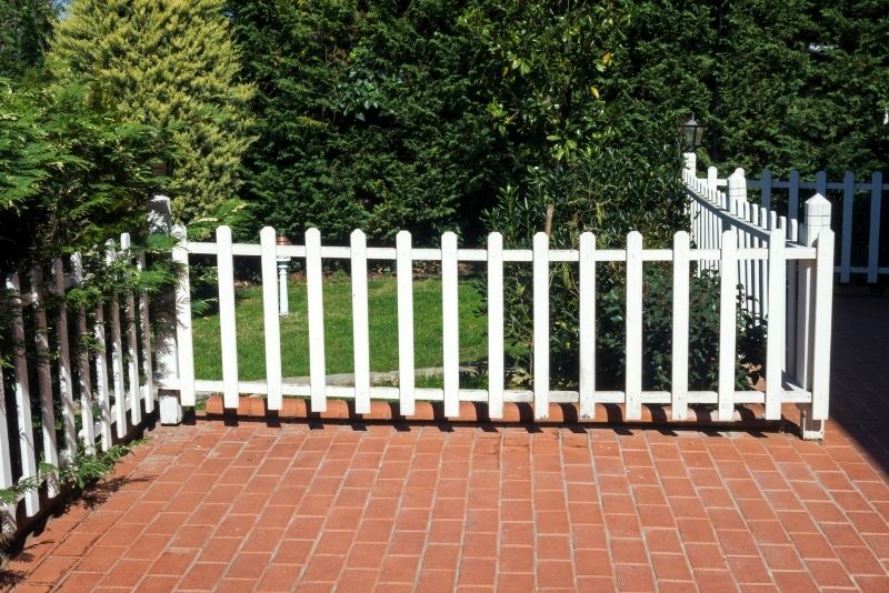 Red brick patio bordered by a white picket fence