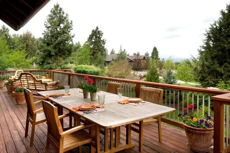 Timber deck with an outdoor dining table overlooking a forested valley